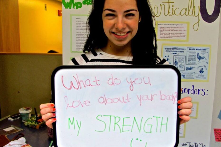 Eating disorder recovery blog-Dark-haired, smiling woman holding a sign that reads: What do you love about your body? My strength!