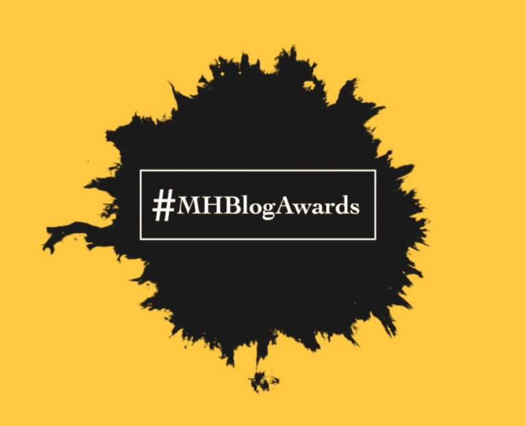 Yellow background with white text in middle that says "#MHBlogAwards"