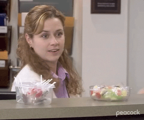 Pam from the Office smiling and holding up bowls of Halloween candy