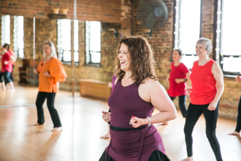 Curly haired woman exercising with other women in the background for post on Eating Disorders Awareness Month
